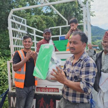 Helfer der Maya Nepalhilfe übergibt verpacktes Küchenset an Betroffenen in Nuwakot.