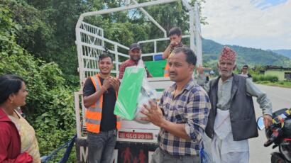Helfer der Maya Nepalhilfe übergibt verpacktes Küchenset an Betroffenen in Nuwakot.