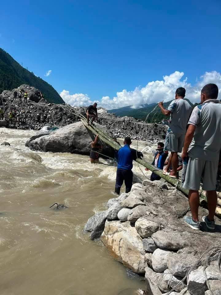 Einheimische sichern Bambusstämme für die Behelfsbrücke nach den Überschwemmungen in Nuwakot.