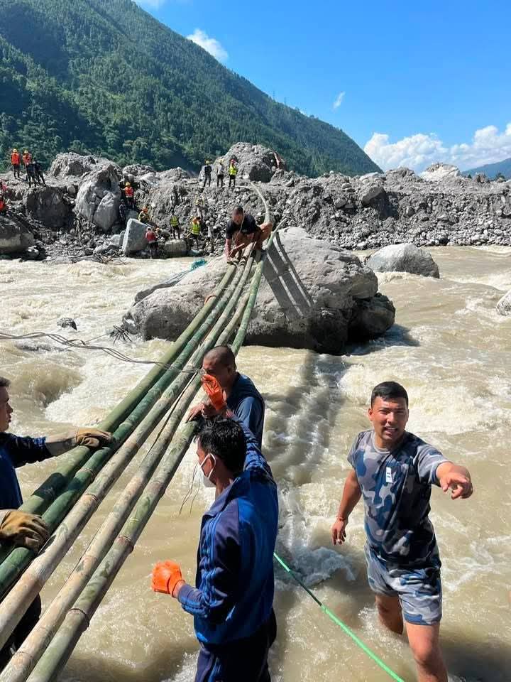 Helfer errichten eine Behelfsbrücke aus Bambus über den reißenden Fluss in Betrawati.